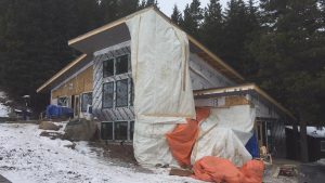 new custom home being built in the winter in alberta next to a forest